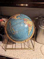Full view of the antique Cram's Imperial 12-inch world globe on its metal stand on a countertop.
