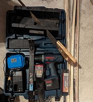 Overall lot with drill in case, batteries, charger, mitre box, handsaw, and several hand tools.