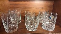 Photo showing six highball glasses grouped on wooden shelf: 2 etched Jihlavske Bohemia Sklarny, 2 hand blown etched Artland, 2 cut crystal with diamond pattern.