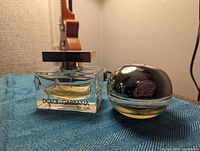 Side and front view of two perfume bottles on a table: Dolce & Gabbana The One and DKNY Be Delicious.