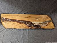 Top view of the full cribbage board showing the wood grain, peg holes, and painted image of bird and landscape.