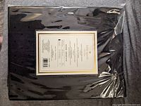 Black Kate Spade tablecloth with visible label showing product details, sealed in original packaging.