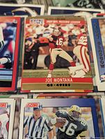 Close-up of Joe Montana NFL Pro Set 1990 trading card showing him in red 49ers uniform with '1990 NFL Passing Leader' header.