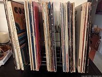 Side view of vinyl record collection illustrating the quantity and condition of album covers with colorful spines, stored in a metal stand.