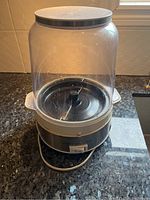 Clear plastic popcorn container with white lid and black base on countertop.