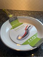Front view of one frying pan showing the label with brand name and product details. The pan is white on the inside with a green handle and a 28cm size label.