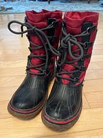 Front and side view of Pajar red winter boots showing lacing, colors, and material.