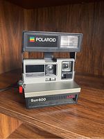 Front view of Polaroid Sun 600 LMS instant camera showing lens, flash, and branding.
