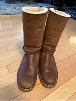 Front view of the brown leather Roots boots showing toe area with smooth leather and strap with buckle.