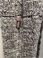 Close-up of knitted fabric texture and Roots brand tag on the scarf.