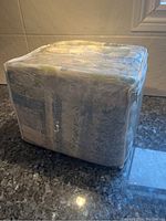 Clear plastic bag containing folded queen size sheet set, seen from side angle showing packaging and product label area.