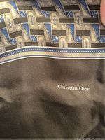 Close-up of the black wool part of the scarf with 'Christian Dior' logo printed in white.
