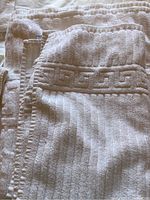 Photo showing folded white towels displaying the embossed geometric border texture