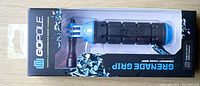 GOPOLE Grenade Grip hand grip in original packaging with clear front showing product inside. The black and blue grip is visible with branding and mounting connection for GoPro cameras.