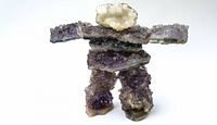Front view of Inuit Inukshuk sculpture made from amethyst and various crystals showing the purple hues and crystalline texture.