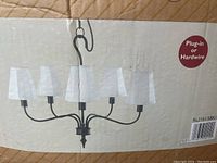Image of the chandelier on box showing 5 lights with beige fabric shades and black finish.
