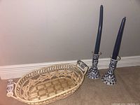 Photo showing the two blue and white porcelain candleholders each fitted with a blue taper candle, alongside the woven breadbasket with porcelain handles.