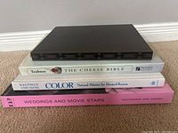 Stack of four coffee table books showing their spines with titles and authors.