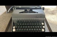 Front view showing the full keyboard with black and white keys, and the Commodore logo on the upper front panel of the typewriter.