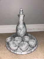 The set arranged on the tray showing the bottle, six cups, and tray in natural marble with smooth edges and polished finish.