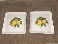 Top view of two square ceramic plates with lemon design on white background.