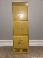Front view showing the full vertical mustard yellow plastic letter holder with three compartments labeled NOTES, a house icon, and MEMOS.
