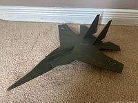 Front angled view of the vintage metal toy plane showing the pointed nose, twin vertical stabilizers, and insignia on one wing.