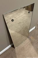 Full view of the vintage rectangular mirror leaning against a wall, showing surface details and reflections.