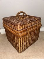 Closed view of the vintage picnic basket showing woven wicker and handle on top.