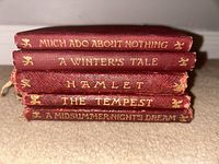 Stack of five vintage miniature Shakespeare books with red covers and gold embossed titles.