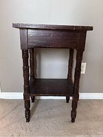 Front view of vintage wooden side table showing turned legs and lower shelf
