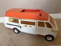 Side view of the vintage Tonka toy van showing orange and white body, decals on side, and overall vintage wear.