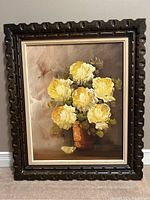 Full view of vintage carved wood frame with painting of yellow flowers in a brown vase.