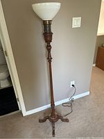 Full view of the vintage wood turned floor lamp standing nearly 5 feet tall with a white glass shade and wooden base on carpeted floor.