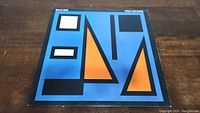 Front cover of Split Enz True Colours album showing geometric artwork in blue, orange, black, and white colors.
