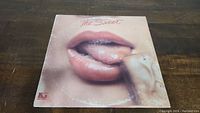 Front cover of The Sweet vinyl record album showing close-up of lips with finger touching them.
