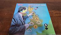Front cover of The Vapors New Clear Days vinyl album featuring a suited man pointing to weather map graphics.
