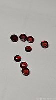 Nine round cabochon garnet stones arranged loosely on plain light background showing various angles and color consistency.