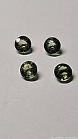 Top-down photo showing four round green sapphire cabochons with reflective surfaces.