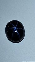 Oval cabochon blue star sapphire showing six-ray star effect centered on the stone