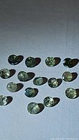 Multiple natural alexandrite gemstones shown individually on white fabric background with visible inclusions.