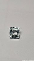Natural aquamarine emerald cut gemstone, viewed from the top showing clarity and cut details.