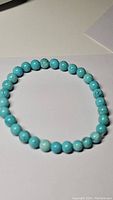 Photo of natural robin's egg blue turquoise bead stretchy bracelet on white background, showcasing round polished beads and marbling.