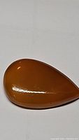 Front view of a large, polished teardrop-shaped yellow onyx gemstone pendant on a white background showing the amber yellow color and smooth reflective surface.