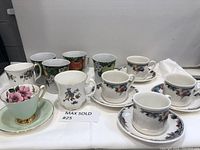 Photo showing all coffee mugs and tea cups and saucers arranged in a row for lot overview