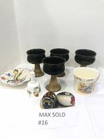 Photo showing 4 dark-glazed stoneware chalices with natural bases, a small hand-painted dish with floral design, a white porcelain bell with painted decoration, two decorated wooden eggs and wooden tray, and a Baby Bunnykins christening mug.