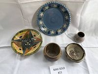 Overview of five pottery pieces on white fabric background