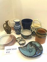 Full lot of 11 ceramic pieces including vases, bowl, basket pot, ashtrays, pitcher, and plates arranged on table