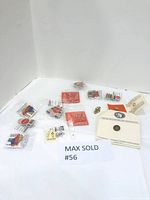 Overview of multiple pins laid on white surface, including several plastic-packaged Coca-Cola Olympic pins and loose pins, some on card backing