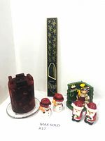 Photo showing the lot contents including the dark green taper candles in box, large red chunky candle on glass plate, and Christmas Santa and snowman candles and figurines